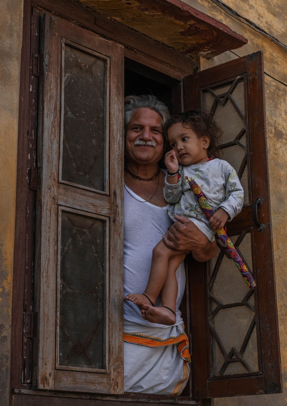 portrait of smiling indian man holding child at window